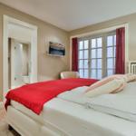 Schlafzimmer mit Bett, Fenster und Bad. Rote Decke und Vorhänge.