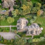 Luftbild einer Villa mit Dachstuhl, Garten und Parkplatz.