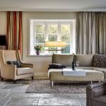 Wohnzimmer mit Ledersofa, Sessel und Fenster mit Blick auf Garten