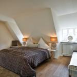 Schlafzimmer mit Dachschrägen, Bett, Sofa und Fenster.