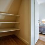 Schlafzimmer mit Dachschräge und Kleiderschrank mit drei Regalen.