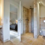 Badezimmer mit Dusche, Toilette und Blick in Schlafzimmer
