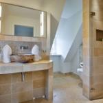 Bad mit Dusche, Waschtisch und Toilette. Fliesen und Spiegel sichtbar.