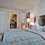 Schlafzimmer mit Bett, Kleiderschrank und Sessel. Durchgang zu einer Treppe.