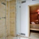 Dusche mit Glaswand und Sauna mit Holzbank und Heizung