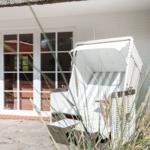 Weißer Strandkorb vor weißem Haus mit Glastür