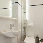 Badezimmer mit Toilette, Waschbecken und Spiegel mit Beleuchtung.