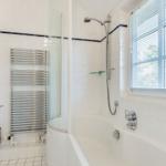 Badezimmer mit Badewanne, Dusche, Toilette und Heizkörper.