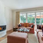 Wohnzimmer mit Kamin, Sofa und Blick auf Garten