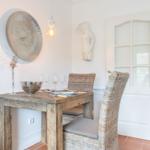 Dining room with rustic table, wicker chairs, and wall decor.