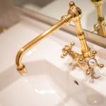 Gold faucet with knobs on white sink
