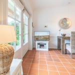 Living and dining area with terracotta floor, TV, and dining table with chairs.