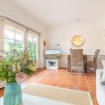 Living and dining area with terracotta floor, TV, dining table, and flower arrangement.