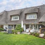 House with thatched roof, garden, and terrace with seating.
