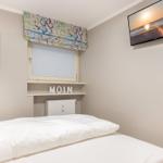 Schlafzimmer mit Bett, TV und Fenster mit Rollladen.