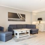 Wohnzimmer mit grauem Sofa, weißem Couchtisch und Wandbild
