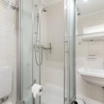 Badezimmer mit Dusche, Waschbecken und Toilette.