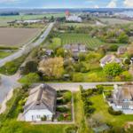 Dorf mit strohgedeckten Häusern und grünen Gärten an der Küste.