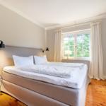 Schlafzimmer mit Bett, Fenster und Holzboden.