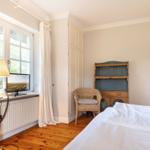 Schlafzimmer mit Bett, Stuhl und TV an Fenster