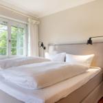 Ein Schlafzimmer mit Doppelbett, Fenster und Wandlampen.