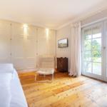Schlafzimmer mit Holzboden, Bett, Schrank und Glastür zum Garten.