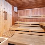 Sauna mit Holzbanken und Temperaturmessgerät an der Wand.