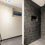 Dusche mit dunklen Mosaikfliesen und Fenster im Bad