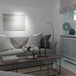 Living room with gray sofa, wooden table, and window with view of greenery.