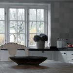 Kitchen with wooden table, two chairs, and view of trees through windows.