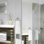 Bathroom with shower and sink. White walls, wooden vanity, and towels.