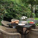 Outdoor dining area with table and chairs, flowers, bread, and vegetables on the table.