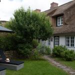 House with thatched roof, garden with loungers and stone path