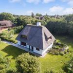 Haus mit Strohdach, Garten und Blick auf weitere Häuser.