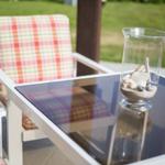 Außenbereich mit Stuhl und Tisch. Auf dem Tisch steht ein Glas mit Steinen und Muscheln.