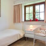 Ein Schlafzimmer mit Bett, Stuhl und Fenster mit Vorhängen.