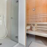 Dusche mit Handbrause und Sauna mit Holzbank und Eimer.