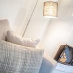 Sofa mit Kissen und Decke, daneben Kamin und Lampe.