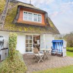 Haus mit strohgedecktem Dach, Terrasse mit Strandkörben und Tisch