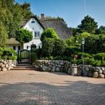 House with thatched roof, stone wall, and paved path.