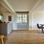 Kitchen with wooden floor, window, and dining area with chair.