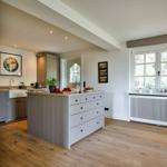 Kitchen with island, wooden floor, and window overlooking garden.