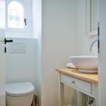 Bathroom with sink, mirror, and toilet under a window