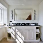 Bathroom with sink, mirror, and window. White furniture and black countertop.