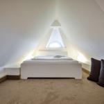 Bedroom with sloped ceiling, white bed, and window