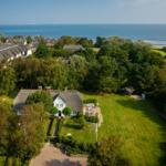 House with roof and garden, surrounded by trees and sea view