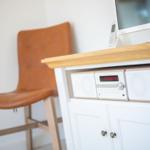 Holzschrank mit Fernseher und brauner Ledersitzbank