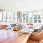 Esstisch mit Stühlen und Fenstern zum Garten