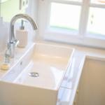 Waschbecken mit Wasserhahn und Seifenflaschen vor Fenster