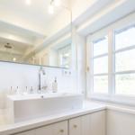 Badezimmer mit Waschbecken, Spiegel und Fenster